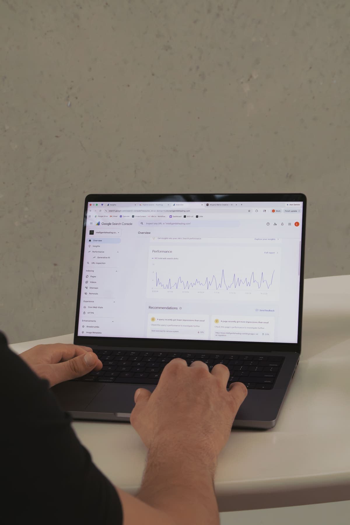 Luke Marinovic's hands on a laptop showing a search performance chart.