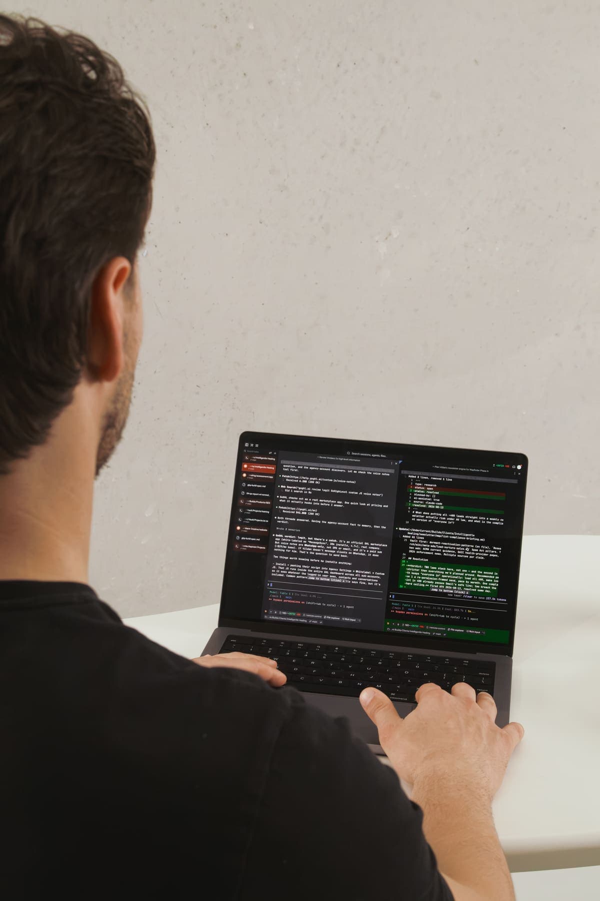 Over-the-shoulder view of Luke Marinovic working in a dark code editor on his laptop.