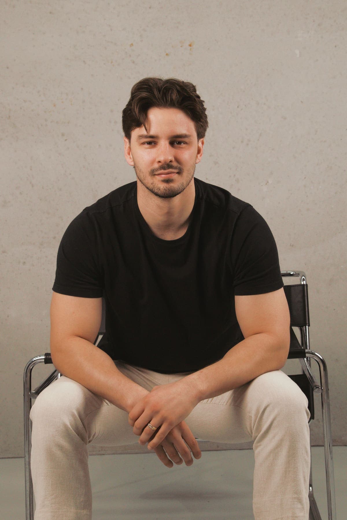 Luke Marinovic seated and leaning forward, elbows on his knees, smiling at the camera.