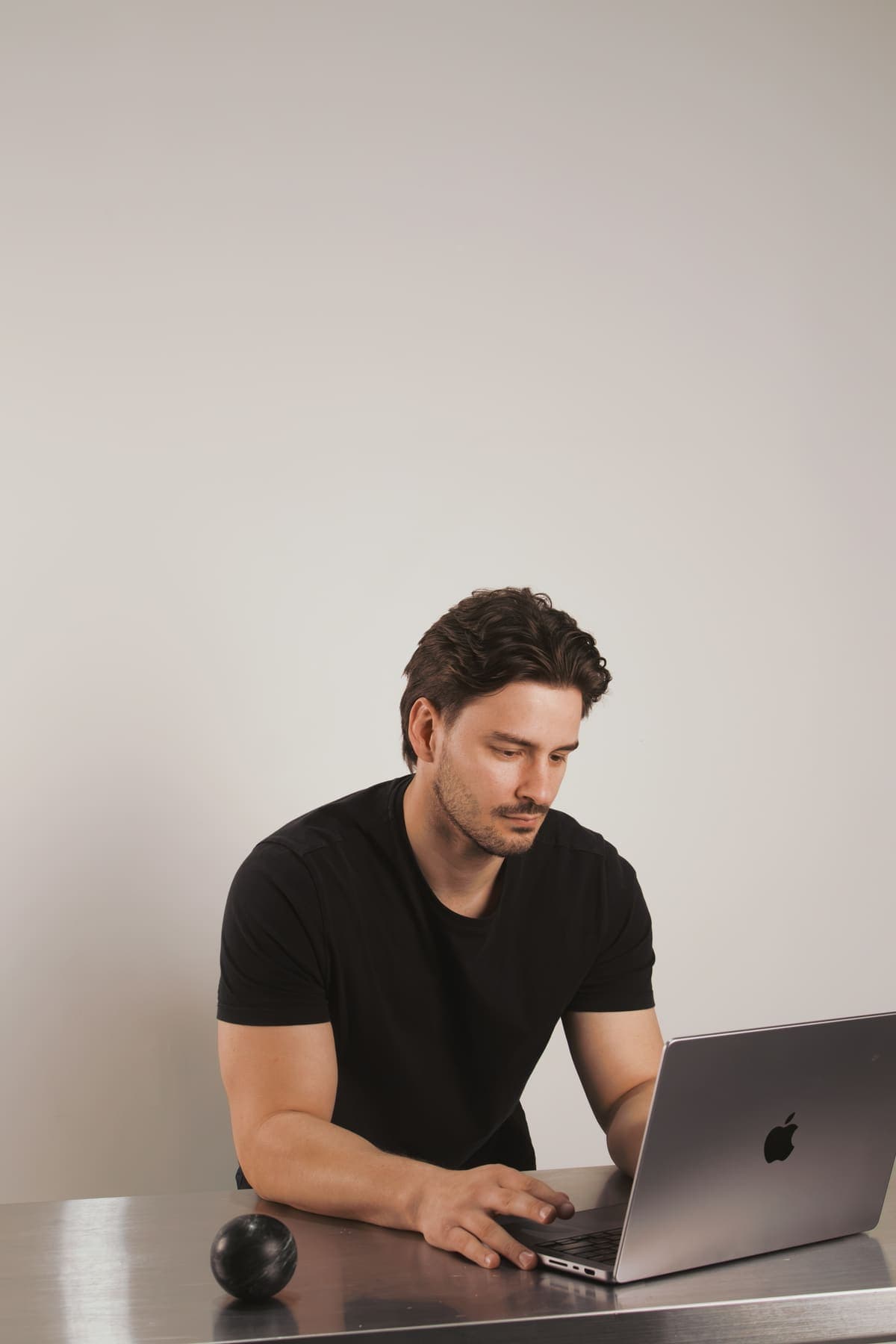 Luke Marinovic looking down at his laptop and typing at a steel desk.