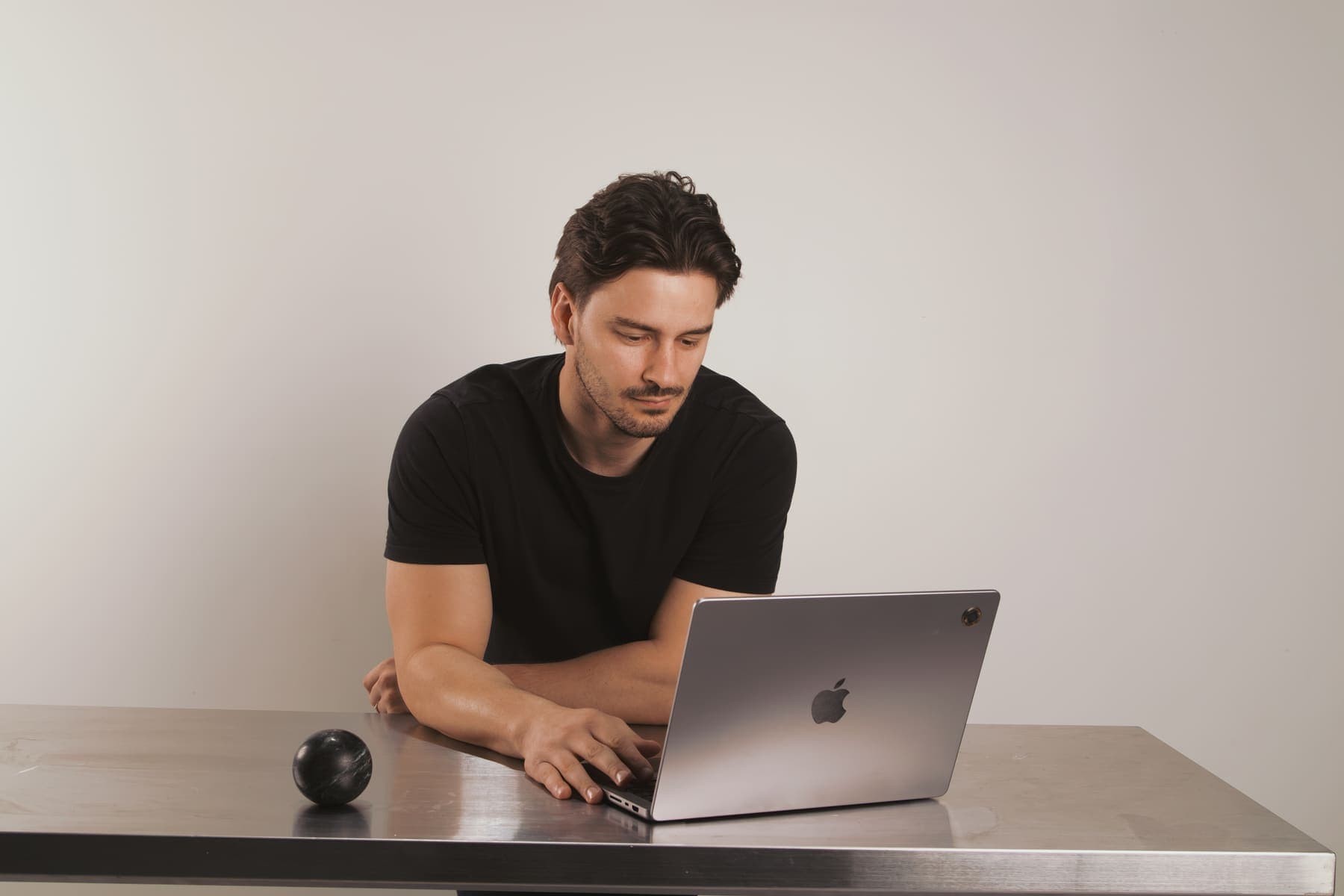 Luke Marinovic typing on a laptop at a steel desk, eyes on the screen.